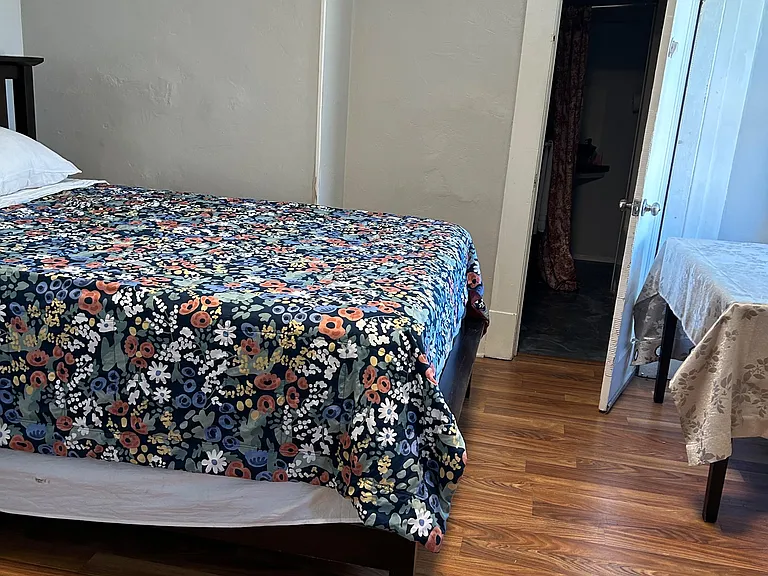 Furnished bedroom with wood-style flooring, a comfortable bed, and convenient access to an adjacent bathroom.