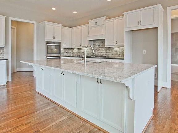 Kitchen with granite countertops, large island, tile backsplash, under cabinet lighting & venthood o
