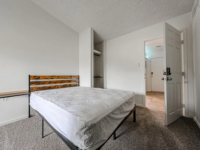 Furnished bedroom with a full bed, open closet storage, and neutral finishes for easy setup and everyday comfort.