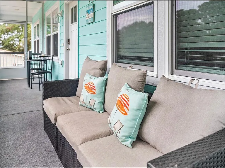 screened porch with a couch and table with chairs