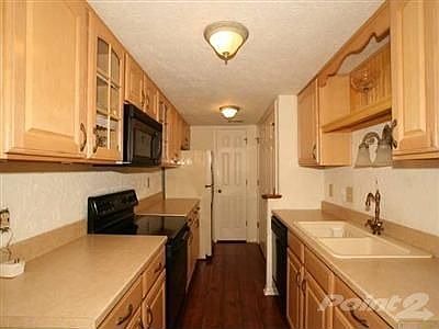Galley kitchen with newer cabinets, newer countertops and laminate flooring.