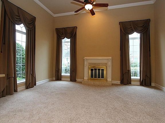 Main living area with custom window covering, fireplace, new carpet, ceiling fan, and double pane windows throughout.