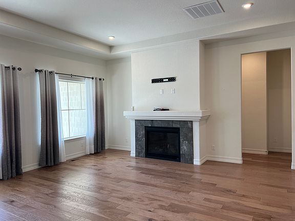 Living room with fireplace, beautiful natural light, wood floors, and window coverings