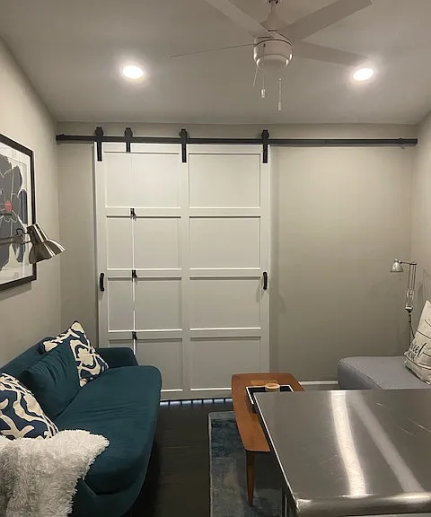 Cozy living room with comfortable high end West Elm loveseat and additional seating for 4. A custom crafted sliding barn door added for additional privacy.