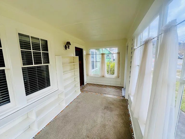 3 season room with bookshelves, glass windows and curtains