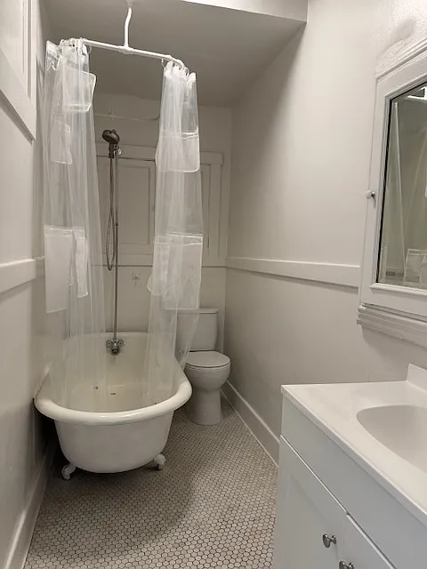 Full size bathroom with shower over clawfoot tub and toilet, plus sink, mirror cabinet and bathroom storage
