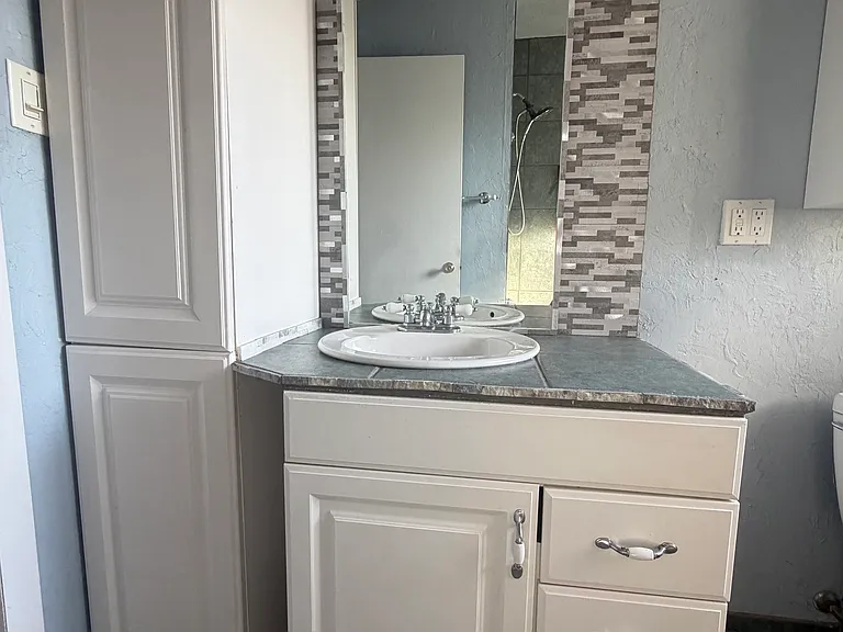 The guest bathroom has been partially renovated and features a new backsplash, updated lighting, and modern finishes that add style and functionality.