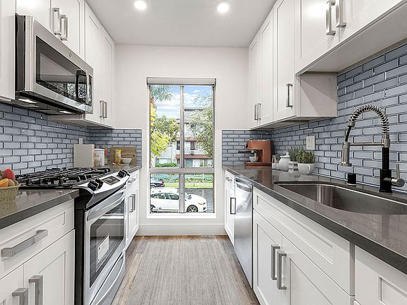 Blue tiled kitchen with stainless steel microwave, oven, and fixtures.