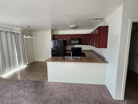 Living room with view into big kitchen dining area. Sliding door opens onto small porch.