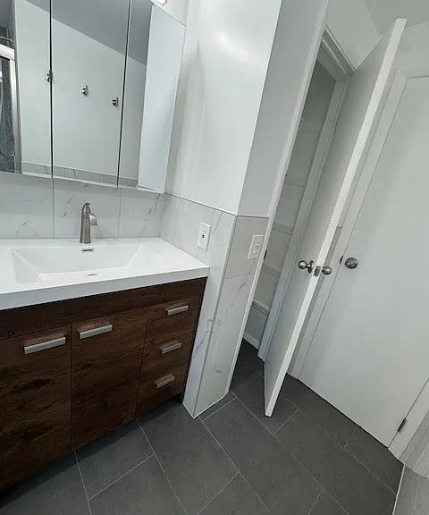 Conveniently located closet in bathroom for linens along with modern, new vanity and mirror for plenty of storage