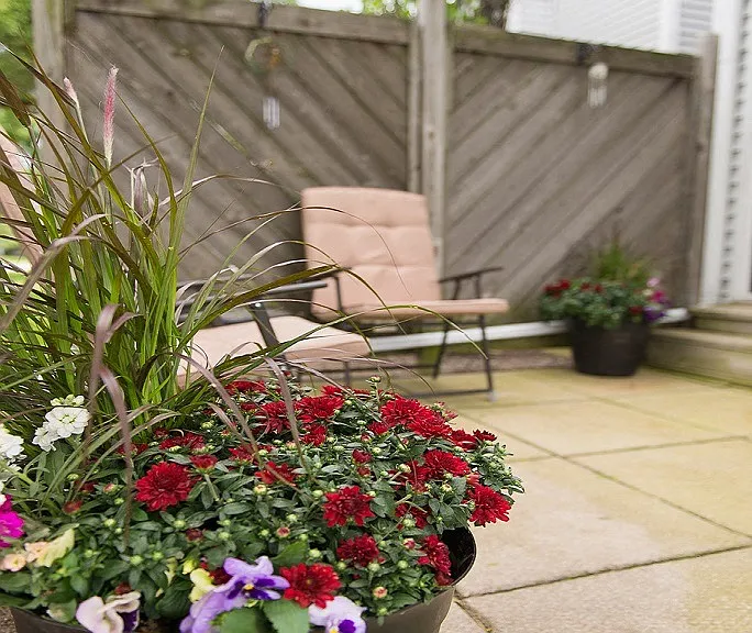 Typical patio with concrete pavers, fence, seating, and flowers