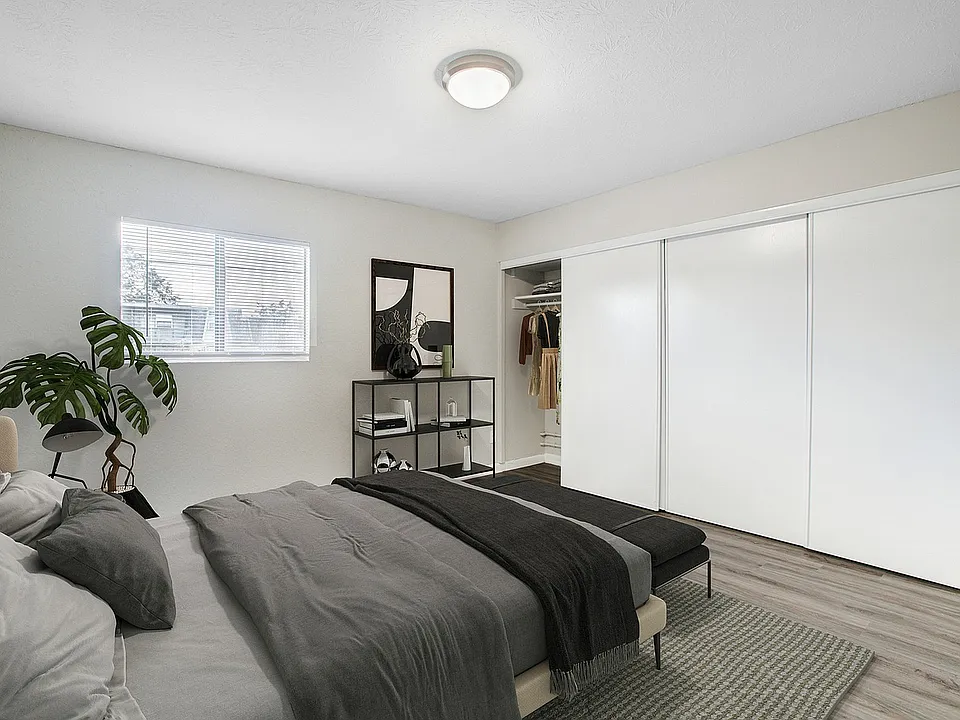 Bright and modern bedroom with stylish decor, spacious closet, and a large window providing natural light.