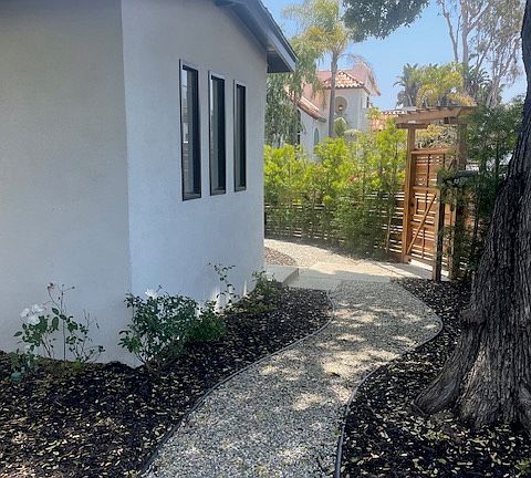 Exterior front with pergola doorway, privacy fence and new privacy trees.