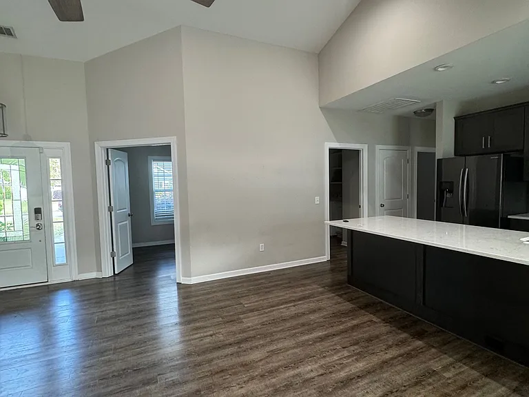 Standing at sliding glass door looking into office and across kitchen to laundry and pantry then hallway to bedrooms.