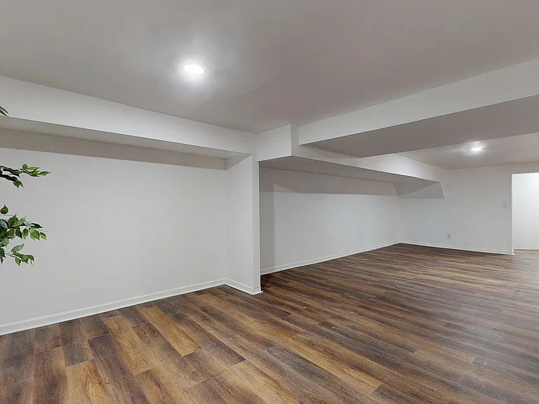 Spacious open common area with durable wood-look flooring, recessed lighting, and flexible layout for seating or a workspace.