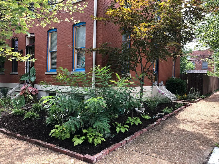 The house is the end unit connected to another townhouse. The front yard features native plants.