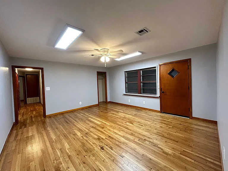 Living room looking at the front door and then down the hallway. Living room has a closet shown in the corner.