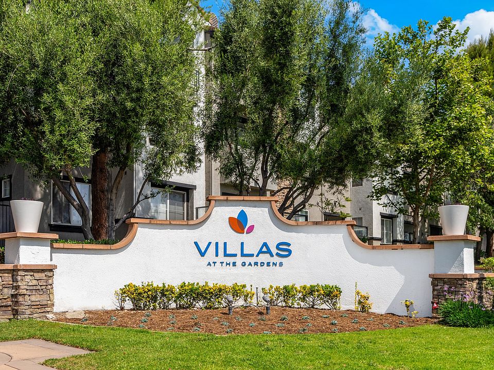 Welcoming Villas at the Gardens Signage Surrounded by Trees and Flowers
