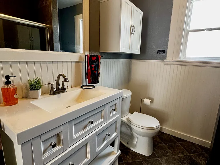 Large mirror, new headboard, and newly painted bathroom. Vanity has four drawers for storage. There is also a cabinet above the toilet. Behind the shower (not pictured) there are tall shelves for storage.