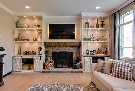Custom built in shelving. Stone and shiplap fireplace with hand hewn beam mantle make this family room a show stopper.