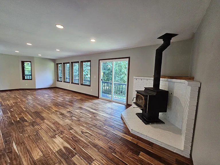 Large, light and bright living room featuring elegant flooring and newly refreshed wood-burning stove for cozy winter nights.