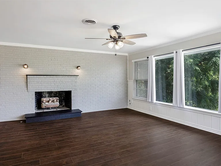 Unfurnished family room featuring dark hardwood / wood-style flooring, ceiling fan, a fireplace, and crown molding