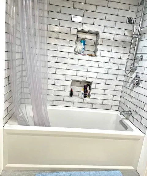 Beautiful soaking tub with subway tile and niche storage