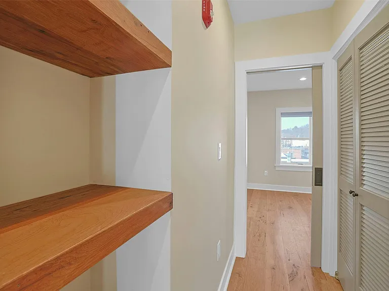 Custom shelves in hallway as you walk toward the sun-filled bedroom. Laundry behind the doors on your right.