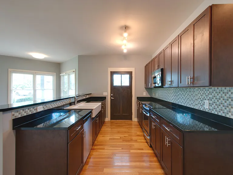 Great kitchen with granite countertops, a tiled backsplash and a convenient side door to bring in groceries