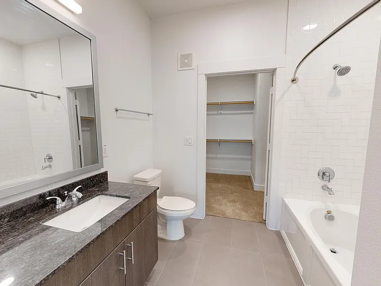 Apartment bathroom with large soaking tub, tile flooring, and double sinks.