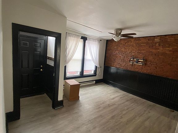 Living room and front door entryway room equipped with jacket and purse hooks, and includes a tv mount attached to the exposed brick wall. Vinyl floors throughout 1st floor.