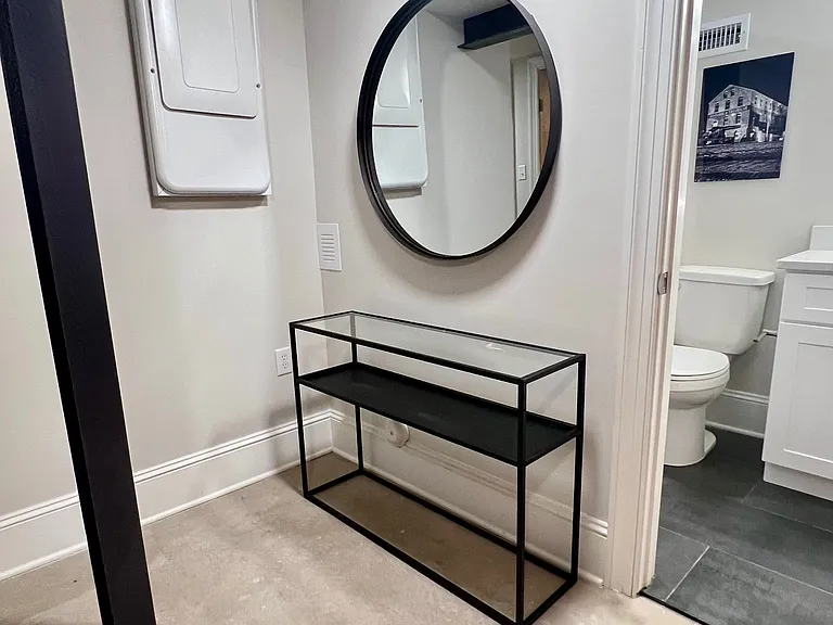 Landing area at bottom of steps with mirror and console table. Secondary bathroom on right side of photo.