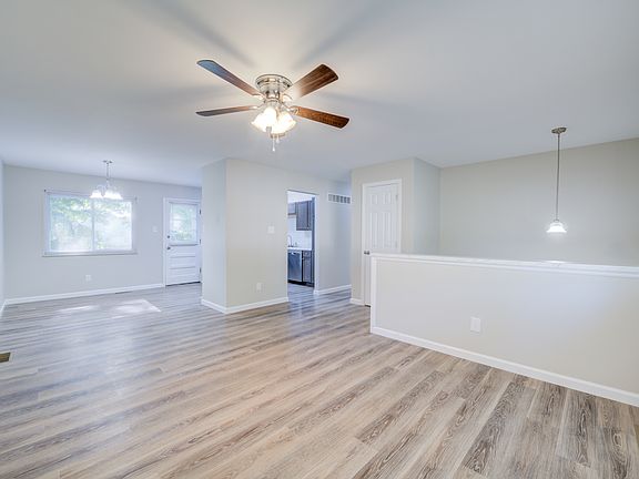 Living room is open to the dining area and kitchen. The door to the deck is in the background.