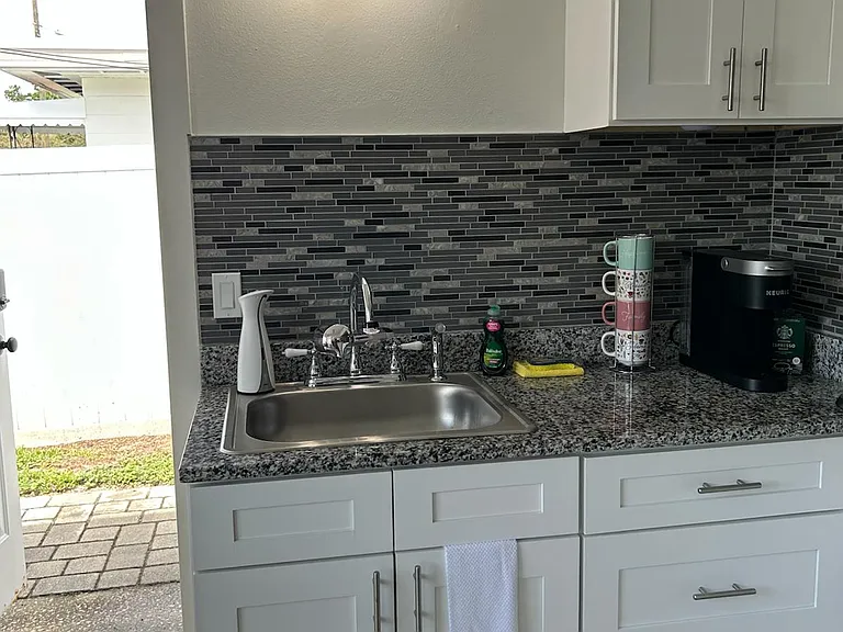 Kitchen with essential amenities, coffee maker, and stylish tile backsplash.