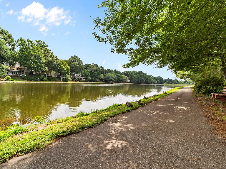 Scenic lakeside walking path with peaceful water views and shaded seating.