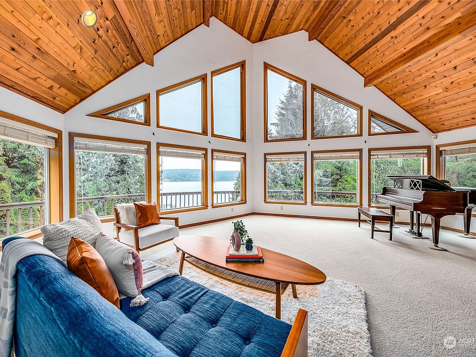 WOW! This stunning living room has a vaulted and beamed ceiling with large windows to let in the natural light.>