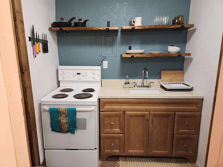 Kitchenette with 4-burner stove, oven, dishes supplied.