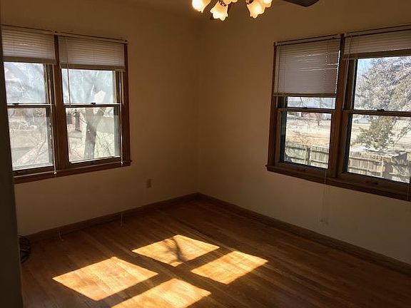 Large bedroom with lots of natural light from the windows and hardwood floor.