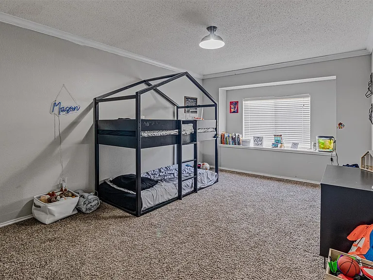 Spacious room featuring carpeting, crown molding, a window with horizontal blinds, a ceiling-mounted light fixture, and light gray wall paint