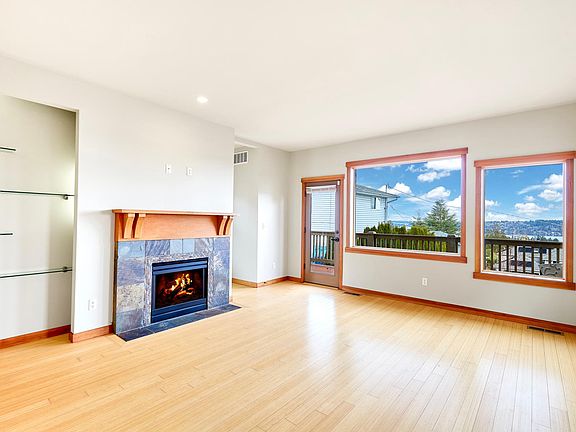 Open concept living room with cozy fireplace and display area - large windows flood the house with light and provide a perfect view of the lake and mountains in the distance.
