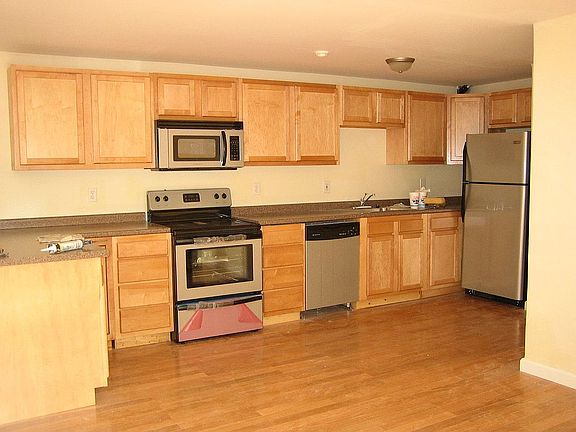 Maple kitchen with stainless appliances open to bright livingroom