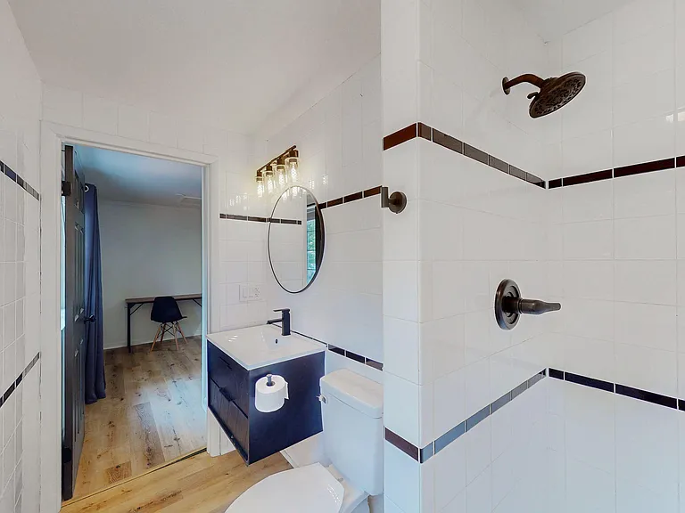 Tiled bathroom with a walk-in shower, updated vanity with round mirror and vanity lighting, plus easy-care finishes.