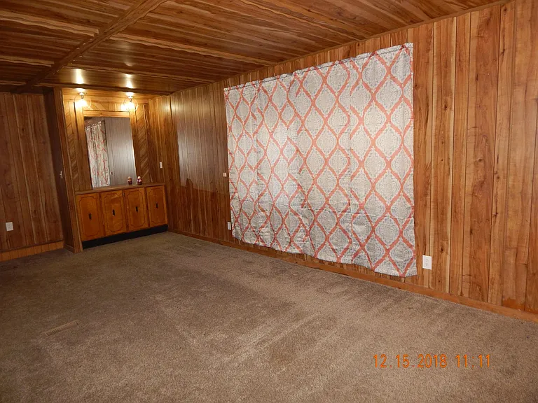 Living room with windows and curtains on the right special cabinets with mirror on the left