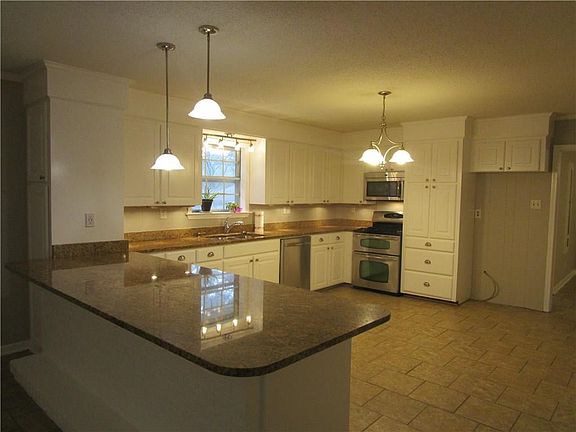 Kitchen with 8 foot long snack bar with granite counter tops & SS appliances.