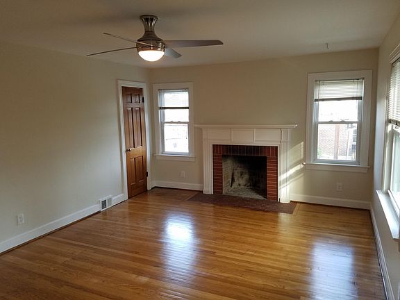 Large living room with beautiful hardwood floors, decorative fireplace, and cool new ceiling fan.