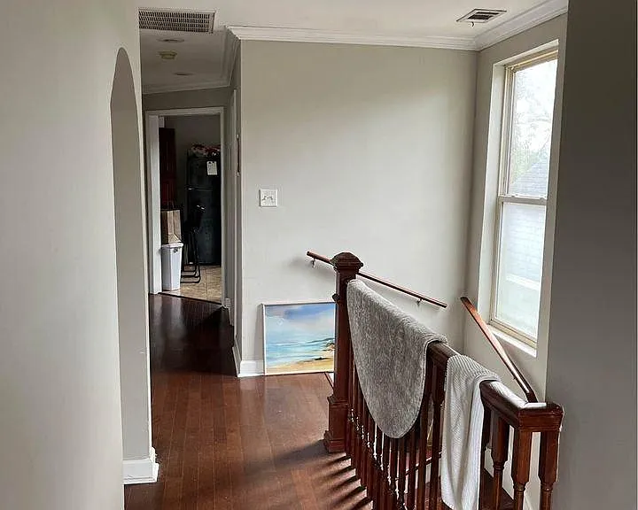 Top-floor entry and staircase landing with hardwood floors and bright hallway.