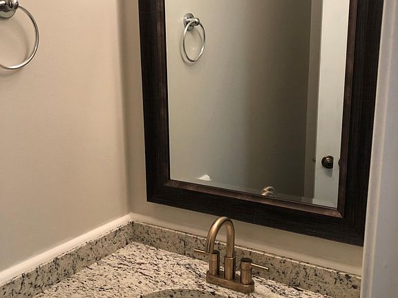 New granite, fixture, mirror and push button water saving toilet.