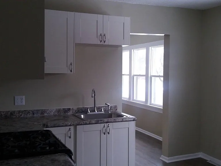 View into living room area from kitchen, windows with lots of natural light throughout