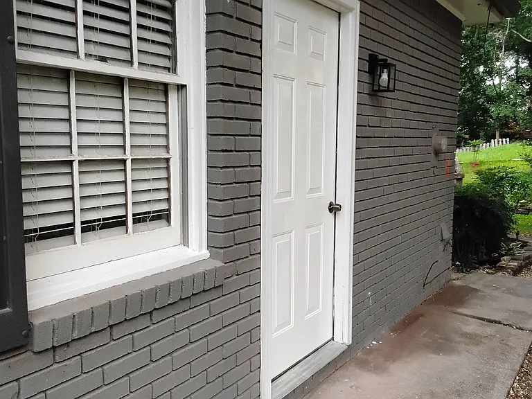 Convenient side entrance with covered eave, exterior light, and a concrete walkway leading to the yard.