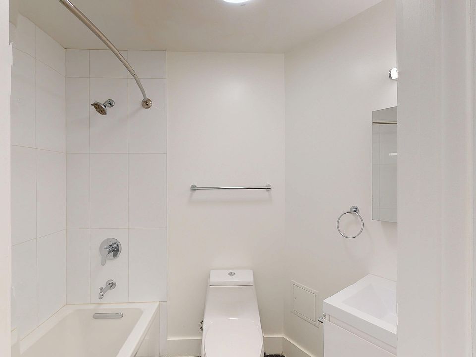 Bathroom featuring a bathtub, toilet, sink, and shower with chrome fixtures against tiled walls